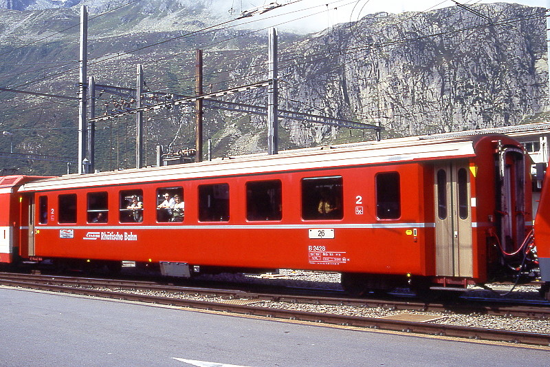 RhB - B 2428 am 25.08.1996 in Andermatt - 2.Klasse Einheitspersonenwagen (Typ II) - �bernahme 05.09.1979 - FFA/SWP/RhB - Fahrzeuggewicht 15,00t - Sitzpl�tze 52/Stehpl�tze 24 - L�P 18,50m - zul�ssige Geschwindigkeit 90 km/h - �3=13.01.1995 - Logo RhB in deutsch - Klassezahlen klein, Griffstangen neben den T�ren entfernt, gelbe Taster neben den T�ren, Kennzeichnung an den Ecken gelb - Hinweis: Die Fahrzeugserie bestand aus 30 Wagen mit den Nummern 2421 bis 2450. 
